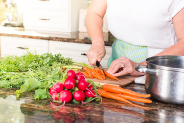 Close-up of woman cutting vegetables in sunny kitchen