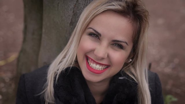 Happy blonde woman laughing looking at camera-outdoor