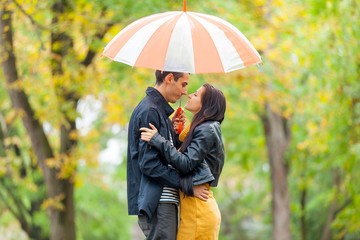 photo of cute couple hugging under umbrella on the wonderful autumn park background