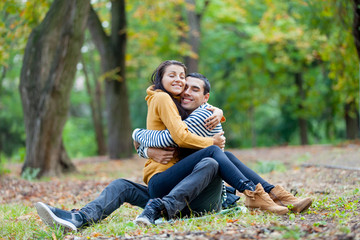 Obraz premium photo of cute couple hugging on the ground on the wonderful autumn park background