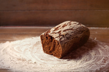photo of tasty fresh loaf of bread on the wonderful brown wooden background
