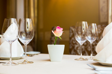Pink rose in a vase as table decoration. Table setting
