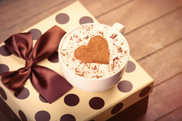 photo of cup of fresh coffee and cute gift on the wonderful brown wooden background
