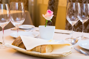 Beautifully decorated table in the restaurant. On the table is a vase with pink rose