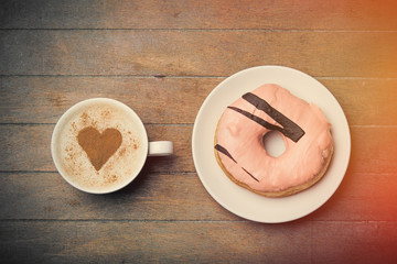 photo of glazed donut and cup of coffee on the wonderful brown wooden background