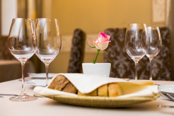 Beautifully decorated table in the restaurant. On the table is a vase with pink rose