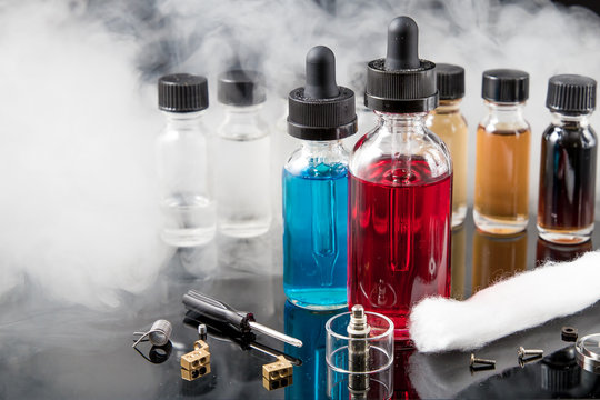 Electronic cigarette liquids with smoke on black background