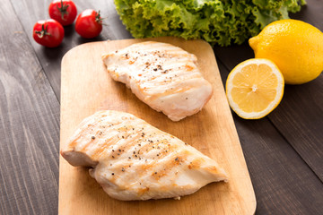 Marinated grilled chicken breasts on the wooden table