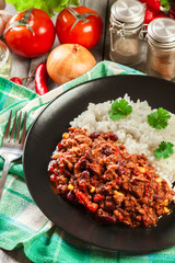 Hot chili con carne with ground beef, beans, tomatoes and corn served with rice