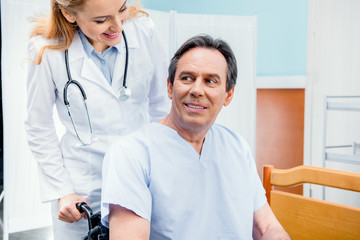 elderly man sitting in wheelchair and doctor standing near him in hospital