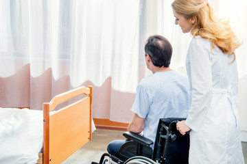 Obraz premium elderly man sitting in wheelchair and doctor standing near him in hospital