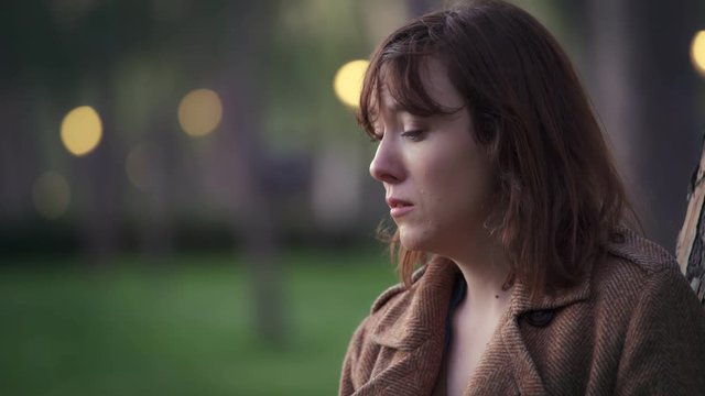 worried,sad woman alone  leaning against a tree,in a deserted park