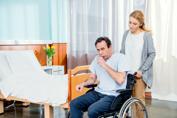 wheelchair man with wife near by in hospital chamber