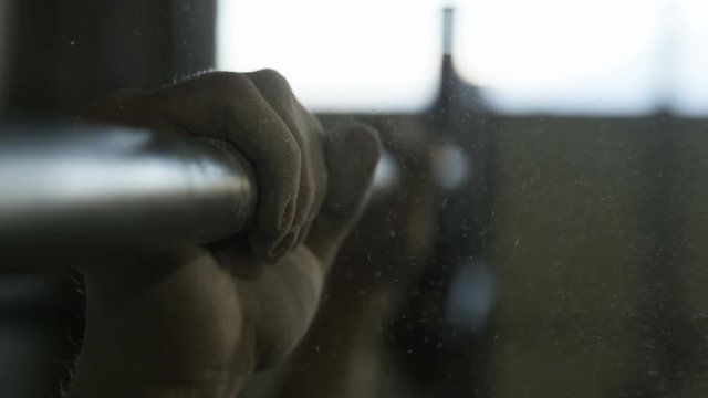 Close-up of a man gripping an athletic bar to do a pull-up