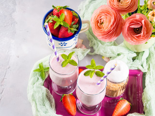 Strawberry milk shake in glasses for romantic breakfast. Summer table setting with ranunculus flowers