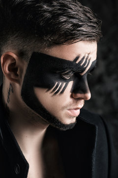 fantasy art makeup. man with black painted mask on face. Close up Portrait. Professional Fashion Makeup.