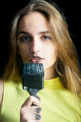 pretty girl builder, painter with black paintbrush, has dirty face