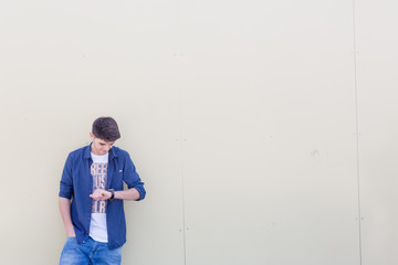 Junger Mann wartet und sieht ungeduldig auf die Uhr