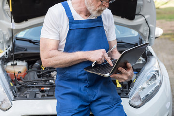 Mechanic using laptop for checking car engine