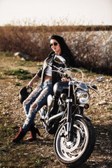Beautiful brunette woman with a classic motorcycle (cinema bleach bypass effect)