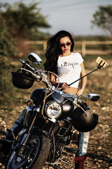 Plakat Beautiful brunette woman with a classic motorcycle (cinema bleach bypass effect)