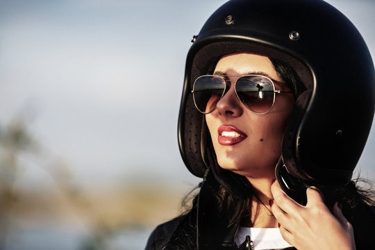 Beautiful brunette woman with a classic motorcycle (cinema bleach bypass effect)