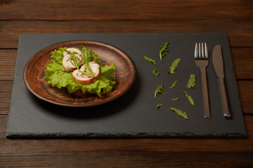 Healthy dinner. A sandwich with baked chicken breast with arugula and lettuce, on a clay plate.