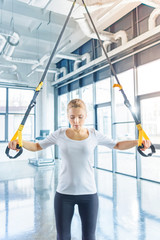 blonde sportswoman training with resistance band in sports center