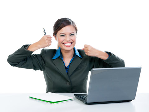Excited businesswoman clenching fists with laptop on work desk over white background