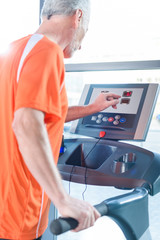 Bearded mature sportsman exercising on treadmill in gym