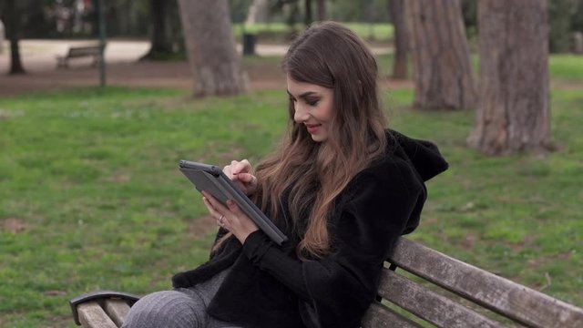 Profile of smiling Beautiful woman sitting bench using tablet