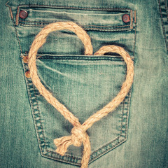 Love heart shaped rope on denim jeans pocket background. Valentine's day card concept