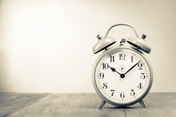 Retro alarm clock on table. Vintage style sepia photo