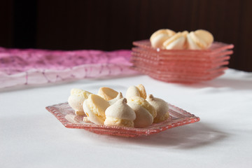 Vase with cookies on a round table. Pink decorative dish with biscuits.