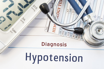 Diagnosis Hypotension. Stethoscope, hematology blood test result and digital tonometer lie on sheet of paper with printed title diagnosis of vascular disease Hypotension