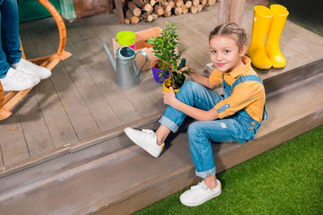 High angle view of adorable little girl sitting on porch and cultivating green plant in pot © LIGHTFIELD STUDIOS