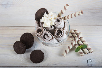Roll of ice cream with crushed chocolate cookies. Fresh fried ice cream, ice roll on a light wooden background