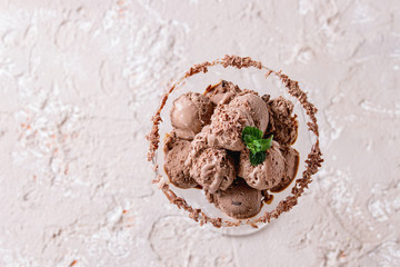 Cocktail glass with chocolate ice cream mini balls on beige concrete texture background background. Top view with space. Dessert concept