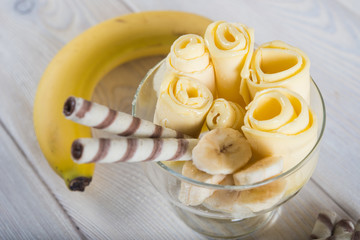 Roll of banana ice cream. Fresh fried fruit ice cream, ice roll on a light wooden background