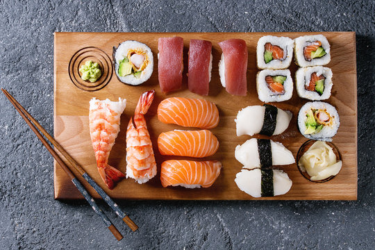 Sushi Set nigiri and sushi rolls on wooden serving board with chopsticks over black stone texture background. Top view with space. Japan menu