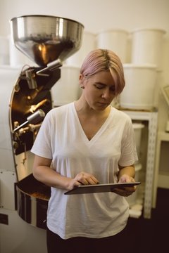 barista using tablet while standing besides coffee 