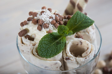 Roll of coconut ice cream. Fresh fried ice cream, ice roll on a light wooden background. Ice cream with coconut bounty