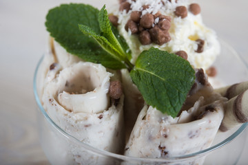 Roll of coconut ice cream. Fresh fried ice cream, ice roll on a light wooden background. Ice cream with coconut bounty