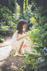 Smiling girl collects flowers in the forest