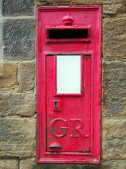 Old British Red post box set in a stone wall with keyhole