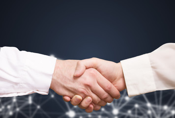 Handshake of two businessmen on an abstract background of technology
