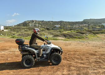 A man riding ATV in sand in a  helmet.