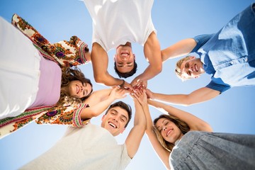 Directly below shot of friends huddling with arms raised