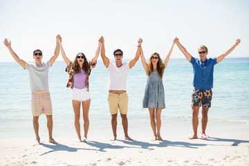 Obraz premium Happy friends with arms raised at beach