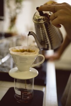 Female barista hands pouring hot water through funnel